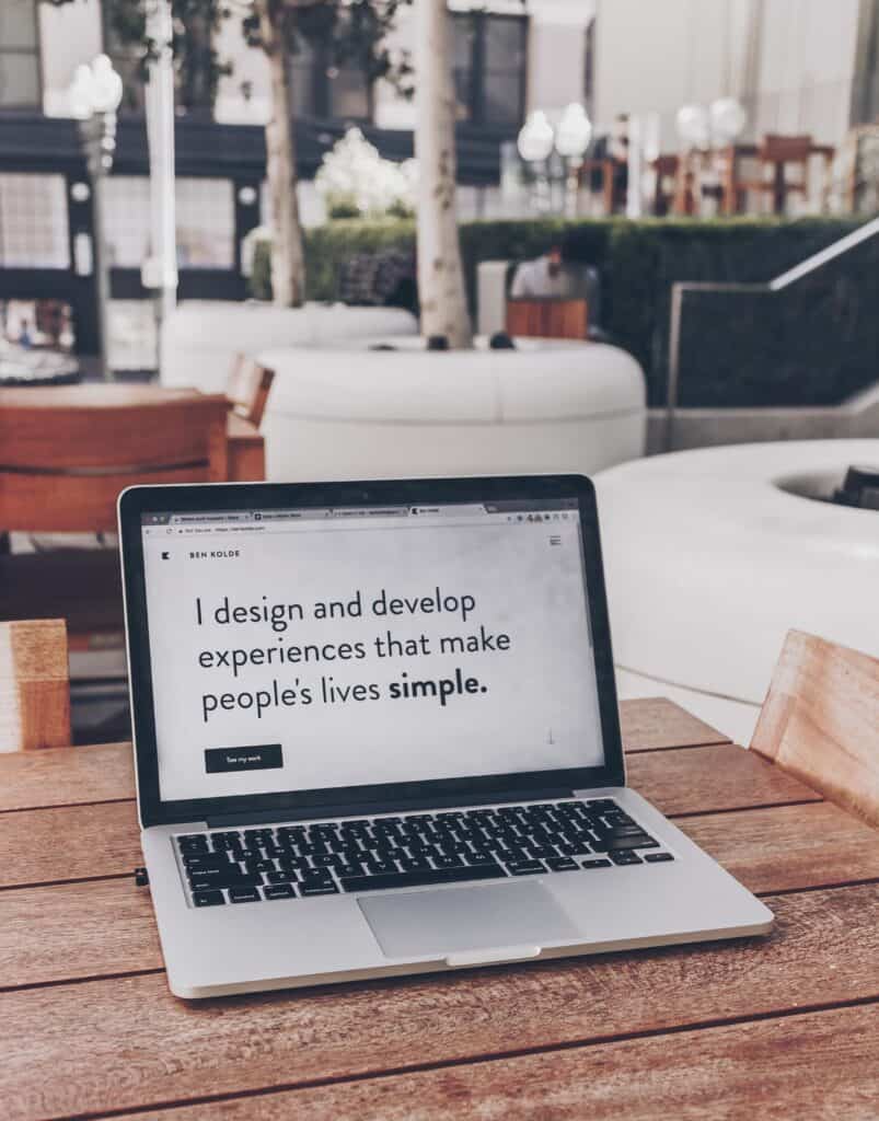 A laptop screen that says 'I design and develop experiences that make people's lives simple