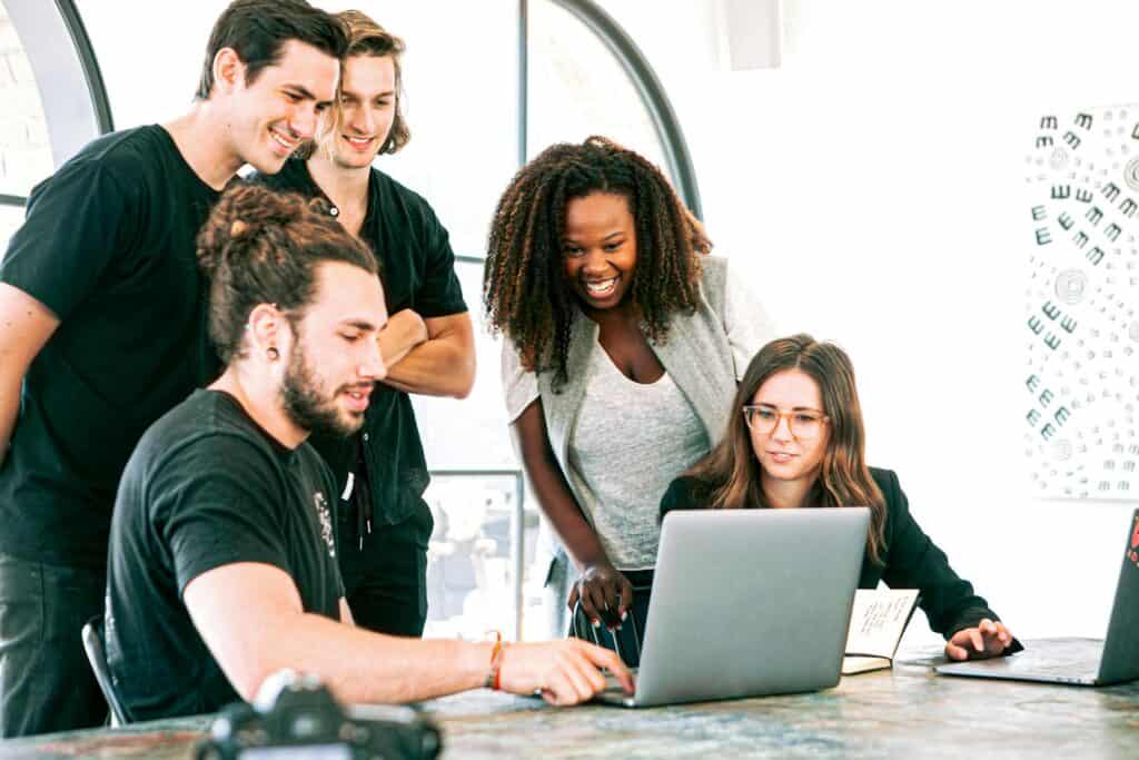 Colleagues gathered around a laptop.