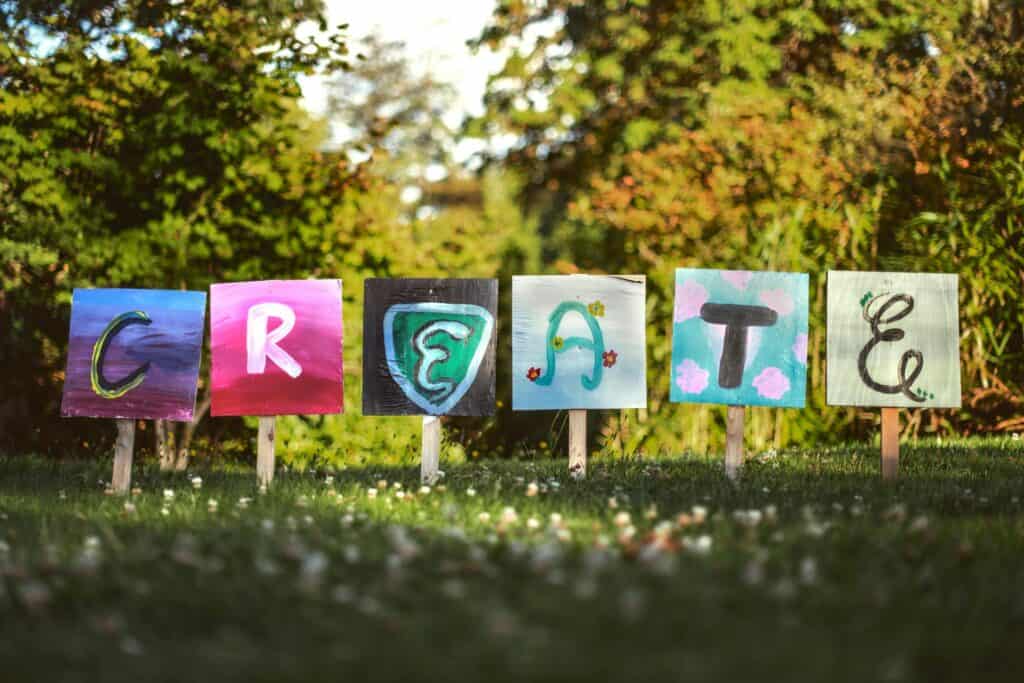 Colourful letters stuck into a lawn, spelling out 'Create'